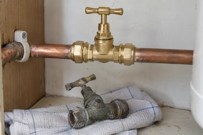 New brass main stopcock with the removed old valve beneath.